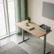 Moderne ergonomische zit-sta bureau in Nederlands kantoor met natuurlijk licht, neutrale tinten en betonnen vloer.
