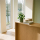 Moderne receptiebalie in een licht Nederlands kantoor met Scandinavisch design, potplant en tijdschrift, natuurlijk daglicht via hoge ramen.
