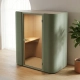 Akoestische telefooncel in modern open kantoor met zacht gestoffeerde wanden, ingebouwde plank en warme verlichting.