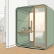 Compacte privacypod met salie groene akoestische panelen en houten plank in lichte Nederlandse kantoorruimte.