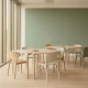 Modulaire lichte houten tafels in flexibele kantoorklas met stapelstoelen, salie groene akoestische wandpanelen en warm daglicht.