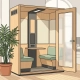 Houten telefooncel in lichte Nederlandse kantoorhoek met matglazen deur, ventilatierooster en weelderige kamerplant ernaast.