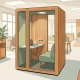 Compacte telefooncel-kantoorpod in modern Nederlands kantoor met warm eiken interieur, ethernet en stopcontact aan de wand.