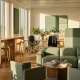 Zonnig open kantoor met modulaire loungezitting, staand werktafel, eiken oppervlakken en salie groene akoestische panelen.