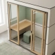Moderne kantoortelefooncel met openslaande schuifdeuren, verlaagd werkblad, eiken accenten en saliegroen interieur.
