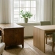 Verouderd eiken bureau met zichtbare houtnerf naast een nieuw exemplaar in een rustig Nederlands kantoor met natuurlijk daglicht.
