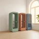 Vrijstaande telefooncel in kantoor in salie groen, terracotta en leisteenblauw, naast plant bij raam met zacht daglicht.