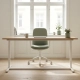 Zit-sta bureau met mat eiken blad en wit frame bij een raam, ergonomische stoel, zachte natuurlijke daglichtinval op lichte houten vloer.